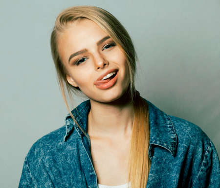 young blond woman on white backgroung gesture thumbs up, isolated emotional posing close up