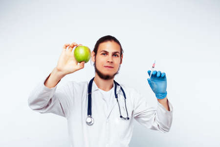 young pretty doctor with stethoscope holding fruits, healthy food care conceptの写真素材