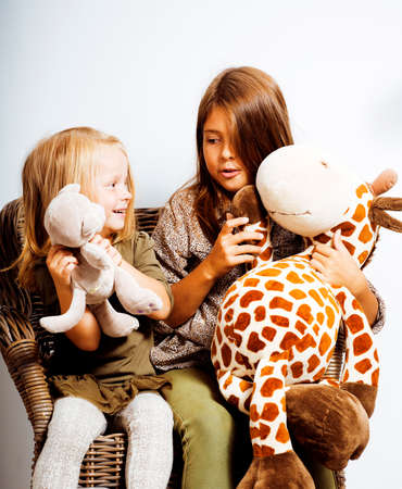 two cute sisters at home playing, little smiling girl in house interior on sofa, messing hair, fighting with pillows, lifestyle people conceptの写真素材