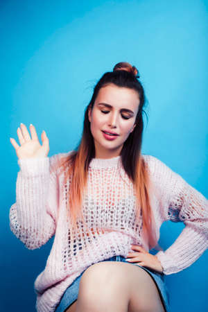 young pretty teenage modern hipster girl posing emotional happy on blue background, lifestyle people...