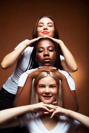 young pretty asian, caucasian, afro woman posing cheerful together on brown background, lifestyle diverse nationality people conceptの写真素材