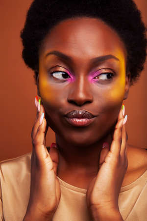 pretty young african american woman with curly hair posing cheerful gesturing on brown background, lifestyle people conceptの写真素材