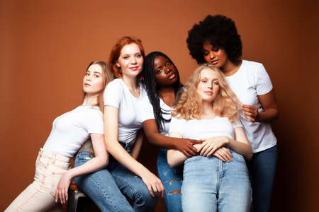 young pretty caucasian, afro, scandinavian woman posing cheerful together on brown background, lifestyle diverse nationality people conceptの写真素材