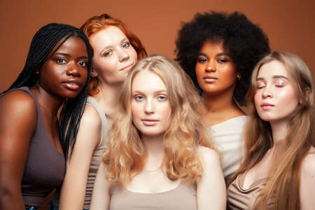 young pretty caucasian, afro, scandinavian woman posing cheerful together on brown background, lifestyle diverse nationality people conceptの写真素材