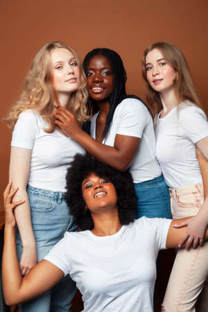 young pretty caucasian, afro, scandinavian woman posing cheerful together on brown background, lifestyle diverse nationality people conceptの写真素材