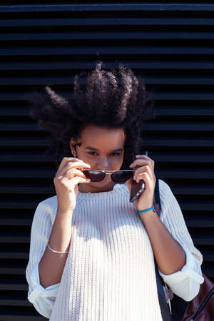 young pretty african girl posing cheerful on city background, lifestyle outdoor people conceptの写真素材