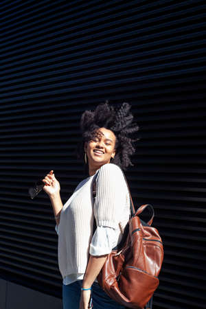 young pretty african girl posing cheerful on city background, lifestyle outdoor people concept