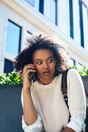 young pretty african girl posing cheerful on city background, lifestyle outdoor people conceptの写真素材