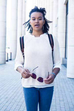 young pretty african girl posing cheerful on city background, lifestyle outdoor people conceptの写真素材