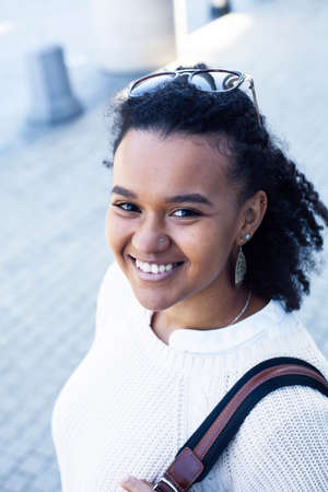 young pretty african girl posing cheerful on city background, lifestyle outdoor people conceptの写真素材