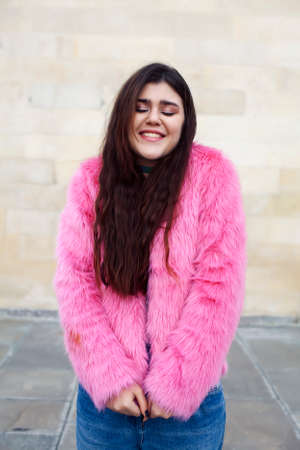young cute girl teenager in pink fur coat gesturing hanging around outdoor , lifestyle people conceptの写真素材