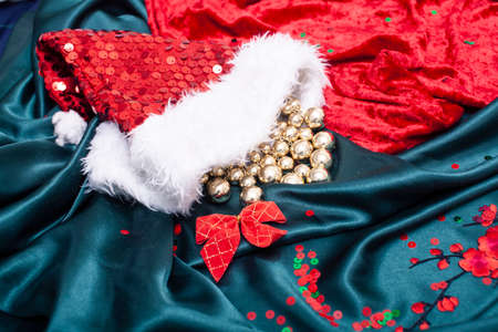 green textured textile with red sakura branch and Santas hat, set design for holiday