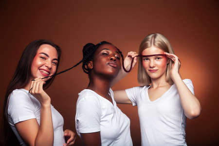 young pretty asian, caucasian, afro woman posing cheerful together on brown background, lifestyle diverse nationality people conceptの写真素材