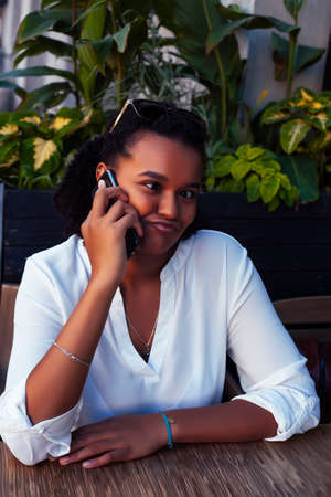 young pretty african girl posing cheerful in cafe outdoor, lifestyle people concept