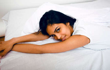 pretty indian brunette real woman in bed smiling, white sheets, tann skin close up mulatto. cant...