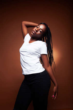 pretty young african american woman posing cheerful gesturing on brown background, lifestyle people...