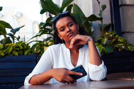 young pretty african girl posing cheerful in cafe outdoor, lifestyle people concept