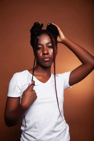 pretty young african american woman with braids posing cheerful gesturing on brown background, lifestyle people conceptの写真素材