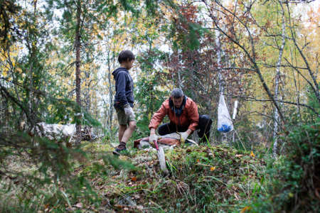 big amount of trash in forest, family father and son picking garbage away, global environment issuesの写真素材
