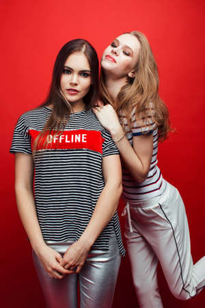 two best friends teenage girls together having fun, posing emotional on red background, lifestyle people conceptの写真素材