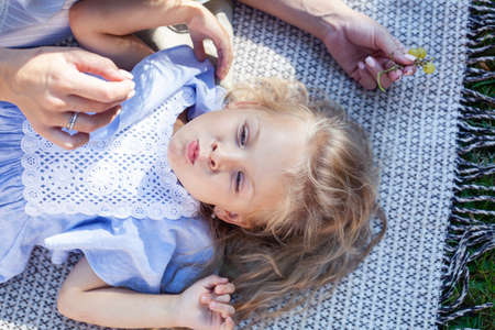 young pretty pregnant brunette woman having fun with her daughter on picnic on green grass in park, lifestyle people conceptの写真素材