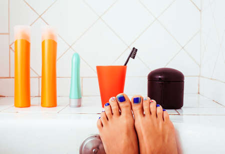 woman legs in bathroom with lot of stylish stuff for care, pedicure creative design, hygiene spa mani pedi conceptの写真素材