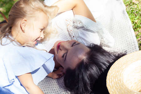 young pretty pregnant brunette woman having fun with her daughter on picnic on green grass in park, lifestyle people conceptの写真素材