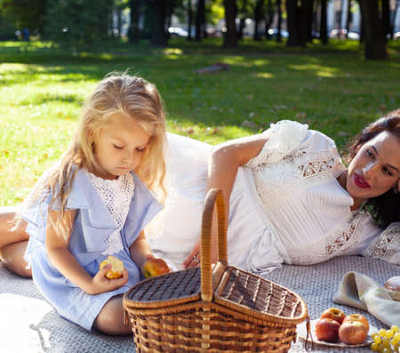 young pretty pregnant brunette woman having fun with her daughter on picnic on green grass in park, lifestyle people conceptの写真素材