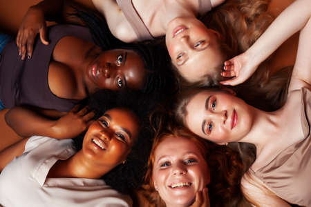 young pretty caucasian, afro, scandinavian woman posing cheerful together on brown background, lifestyle diverse nationality people conceptの写真素材
