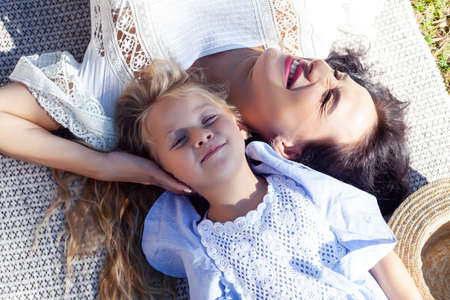 young pretty pregnant brunette woman having fun with her daughter on picnic on green grass in park, lifestyle people conceptの写真素材