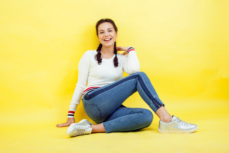 lifestyle people concept: pretty young school teenage girl having fun happy smiling on yellow backgroundの写真素材