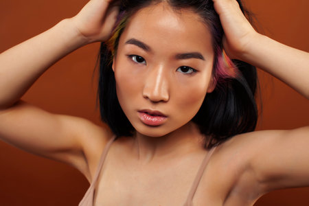 young pretty asian woman cheerful smiling posing on warm brown background, lifestyle people conceptの写真素材