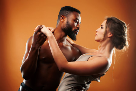 oung pretty couple diverse races together posing sensitive on brown background, lifestyle people conceptの写真素材
