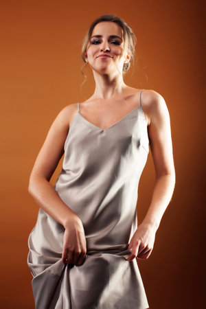 young pretty girl with blond hair in dress posing cheerful on brown background, lifestyle people conceptの写真素材