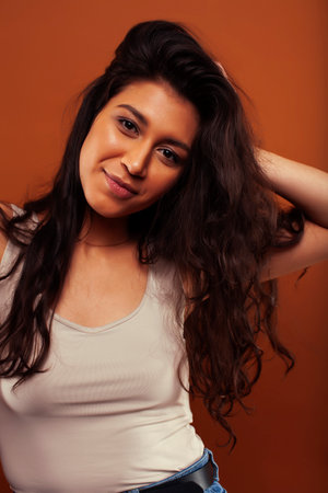 young pretty girl with curly hair posing cheerful on brown background, lifestyle people conceptの写真素材