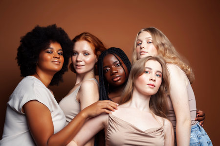young pretty caucasian, afro, scandinavian woman posing cheerful together on brown background, lifestyle diverse nationality people conceptの写真素材