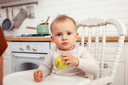 little cute boy in chair on kitchen in morning, lifestyle people conceptの写真素材