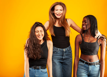 diverse multi nation girls group, teenage friends company cheerful having fun, happy smiling, cute posing on yellow background, lifestyle people concept, african-american, asian and caucasianの写真素材