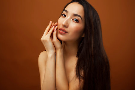 young pretty asian woman cheerful smiling posing on warm brown background, lifestyle people conceptの写真素材