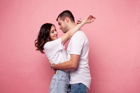 young cheerful caucasian couple together having fun on pink background, guy ang girl modern...