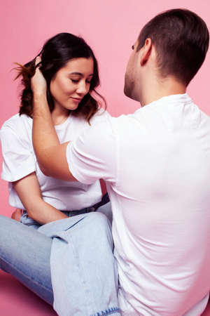 young cheerful caucasian couple together having fun on pink background, guy ang girl modern...