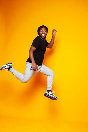 young handsome african american guy student posing cheerful and gesturing on yellow background, lifestyle people conceptの写真素材