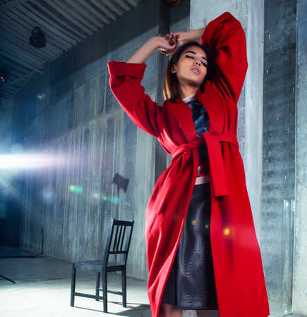 young pretty african american woman in luxury red coat posing fashionable on empty parking building, lifestyle rich people conceptの写真素材