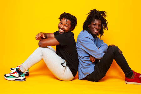 two african american guys posing cheerful together on yellow background, lifestyle people conceptの写真素材