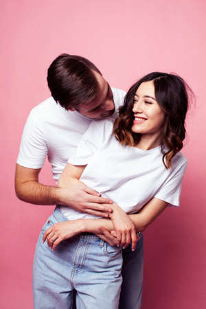 young cheerful caucasian couple together having fun on pink background, guy ang girl modern...