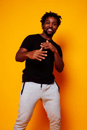 young handsome african american guy student posing cheerful and gesturing on yellow background, lifestyle people conceptの写真素材