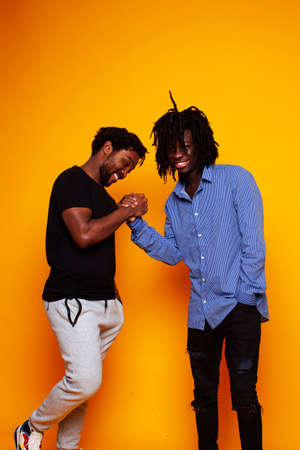 two african american guys posing cheerful together on yellow background, lifestyle people conceptの写真素材