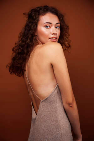young pretty girl with blond curly hair posing cheerful on brown background, lifestyle people conceptの写真素材