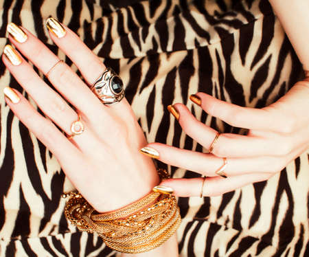 woman hands with golden manicure lot of jewelry on fancy dress closeup beauty concept