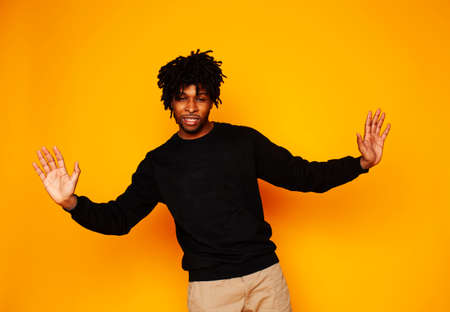 young handsome african american guy student posing cheerful and gesturing on yellow background,...